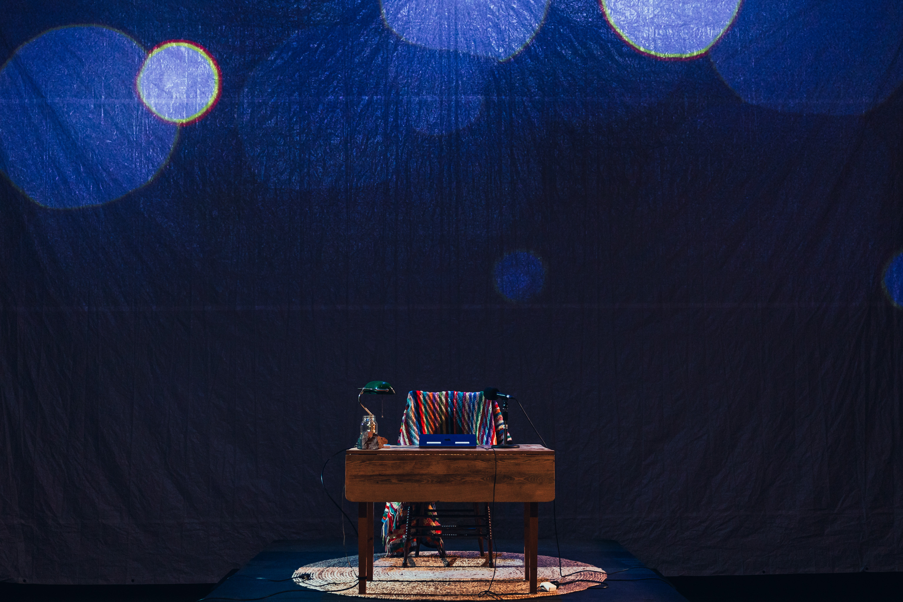 The set of Final Recordings... an antique chair and table on top of a circular cottage rug. 
