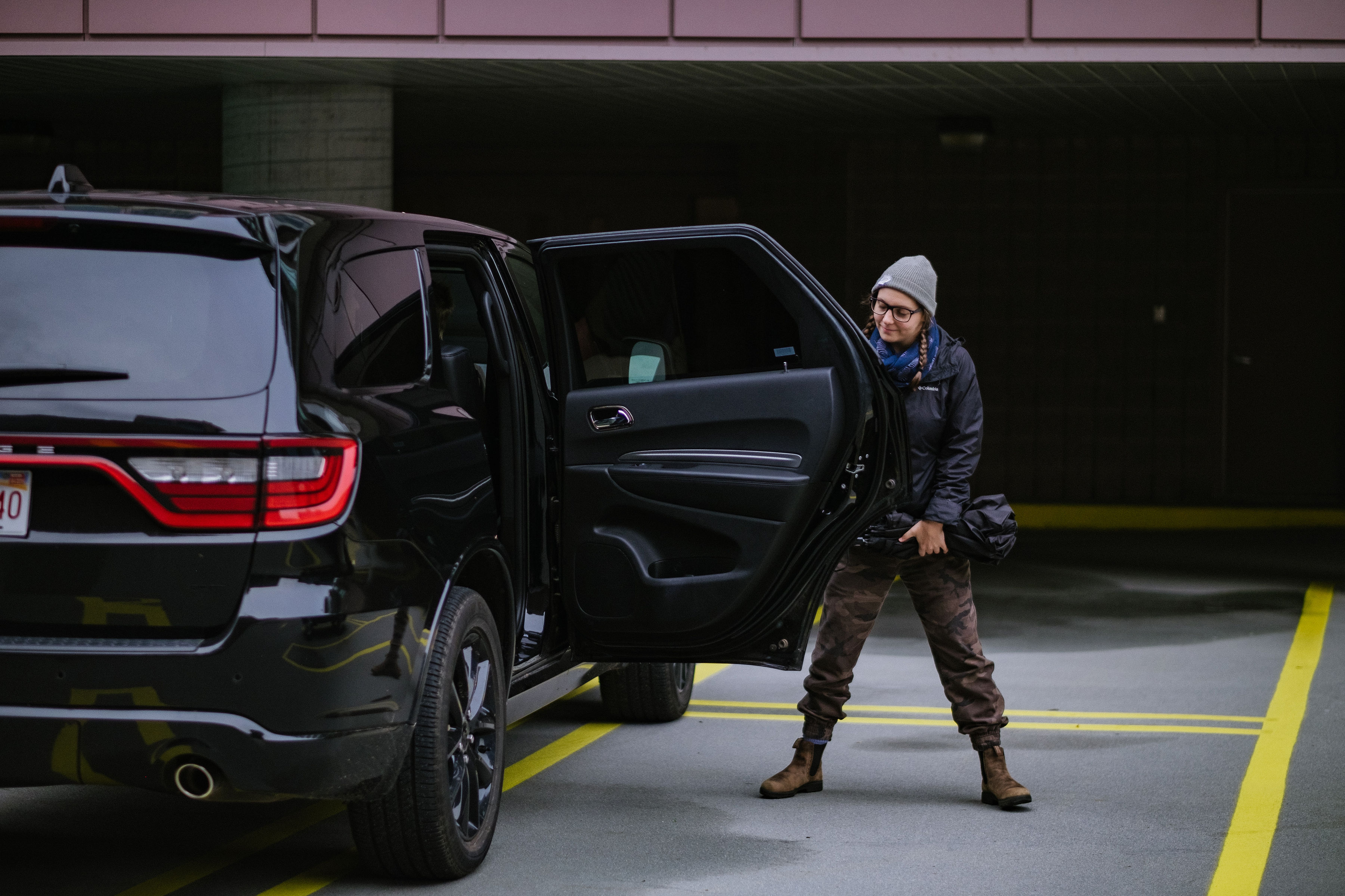 A woman stands next to a vehicle with the door open. Do you get in or not?